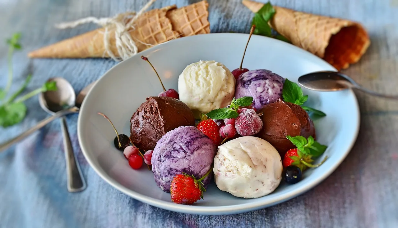 Kleurrijke gelato bollen in een bord met kersen en munt